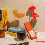 Taste, different drinks like coffee, tea, and cocktail, and some chocolate surrounded by books